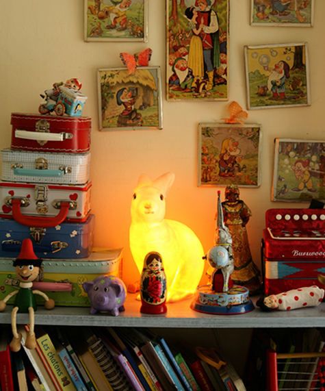 there are many books and toys on the shelf in front of the light up lamp