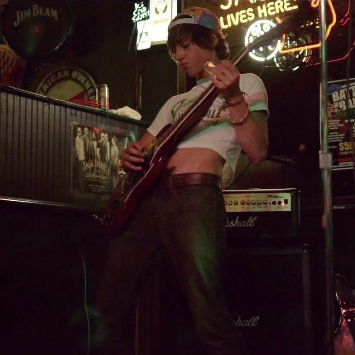 a man with a guitar standing in front of a bar