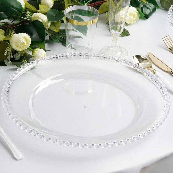 the table is set with white roses and gold cutlery, along with silverware