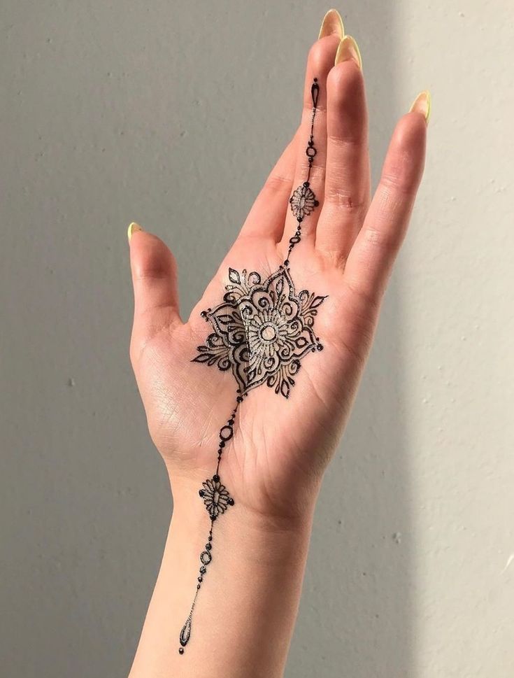 a woman's hand with a henna tattoo on her left arm and wrist