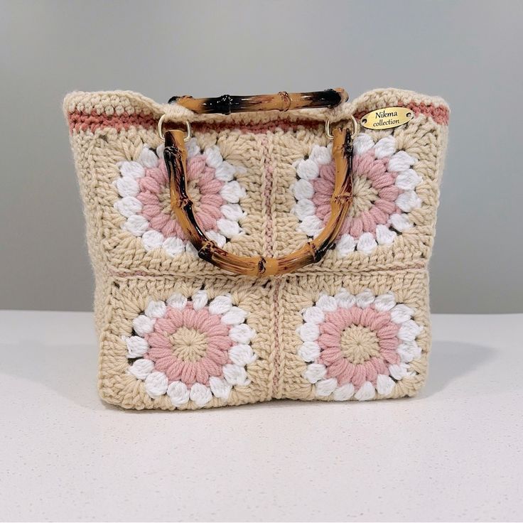 a crocheted bag with flowers on the front and handles is sitting on a table