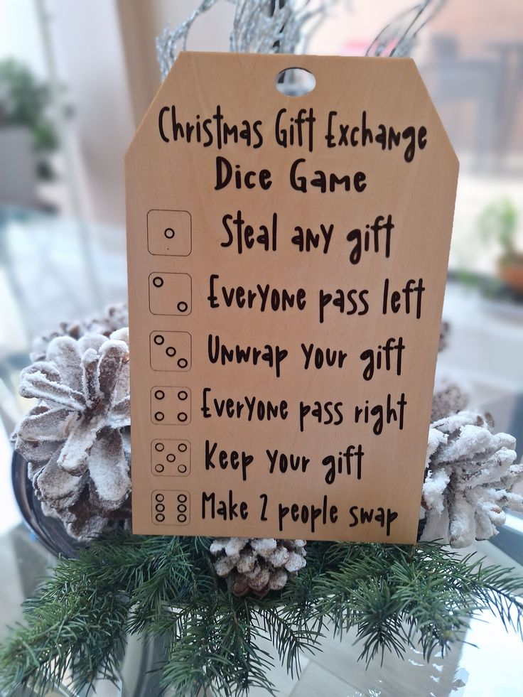 a christmas gift exchange sign on top of a table with pine cones and evergreen branches