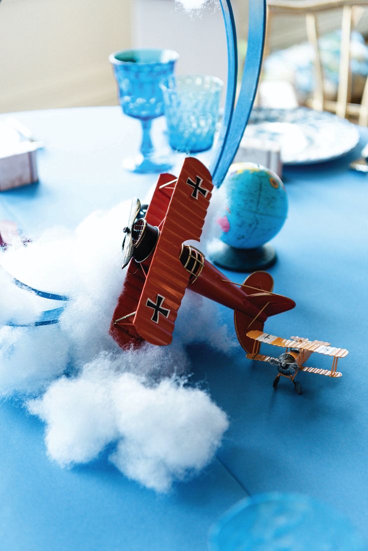 a toy airplane is flying through the air on a table with clouds and blue plates