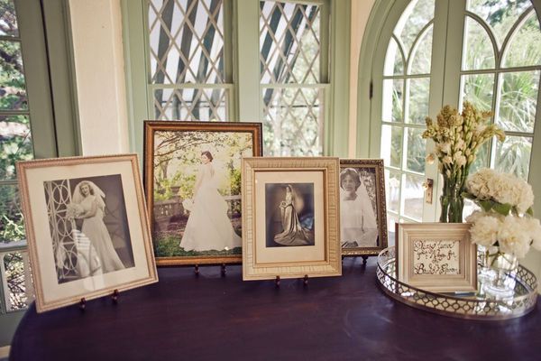 a table topped with pictures and vases filled with flowers next to two framed photos