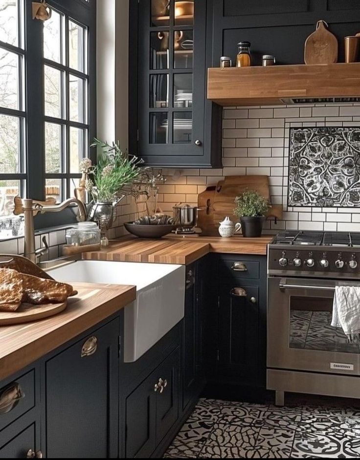 a kitchen with black cabinets and white tile backsplash, wood counter tops, and stainless steel appliances