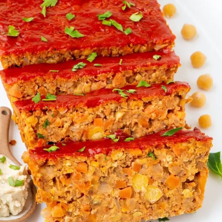 three slices of meatloaf sitting on top of a white plate next to a spoon