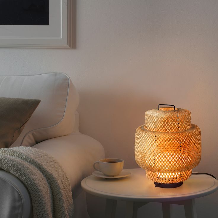 a table with a lit candle on it next to a white couch and coffee cup