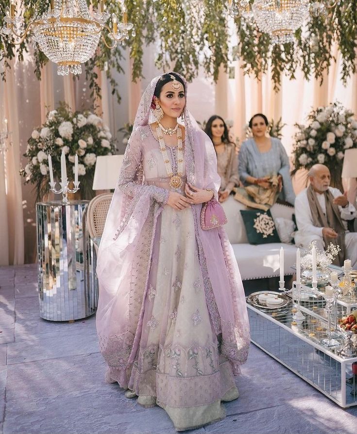 a woman in a pink and white wedding dress standing next to a table full of people