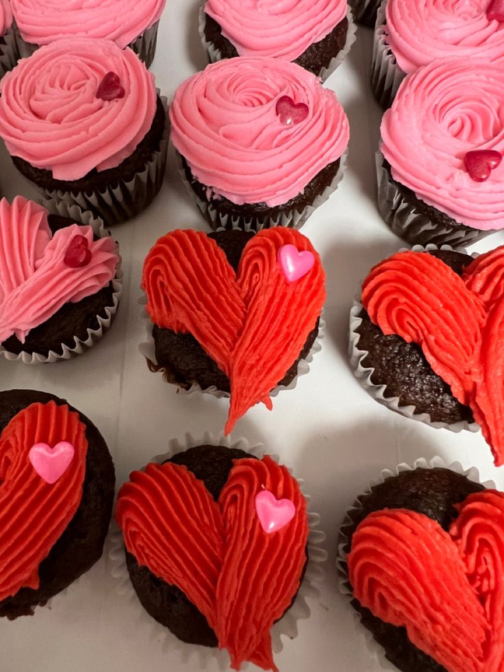 cupcakes with pink frosting and red icing in the shape of hearts