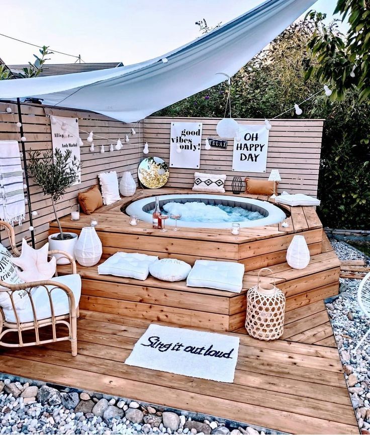 a hot tub sitting on top of a wooden deck next to a white awning