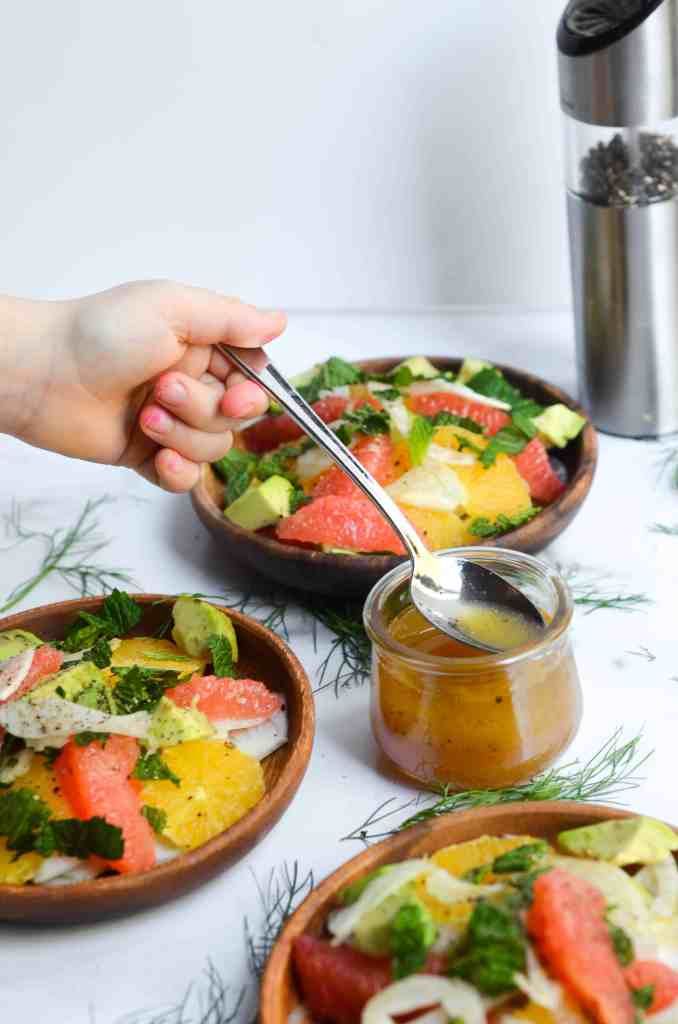 a person is spooning something out of a bowl filled with vegetables and other food