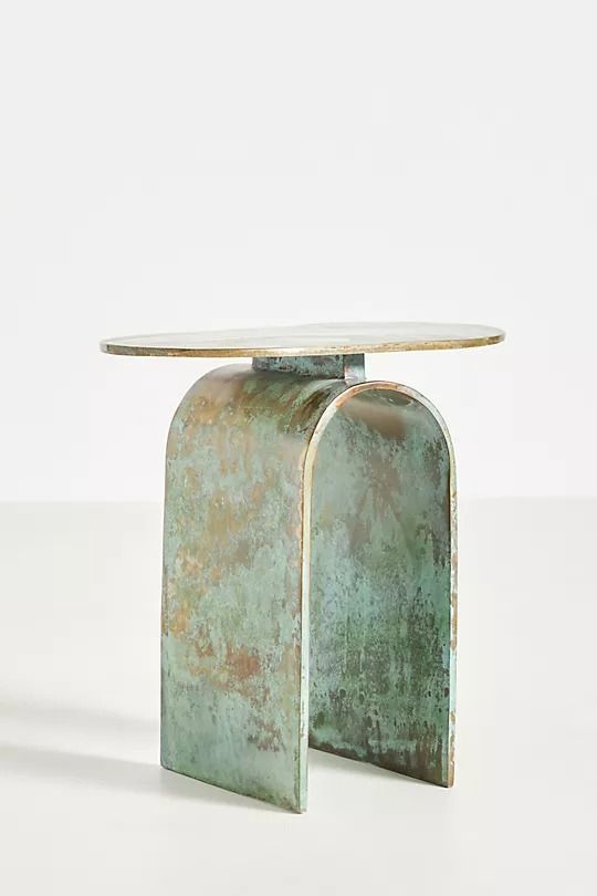 a metal table with a glass top on the side and an oval shaped base in the middle