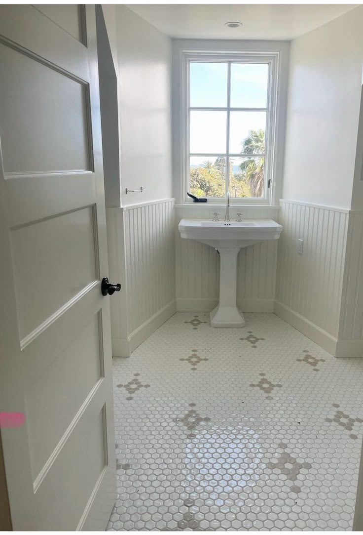 a bathroom with a sink, window and tiled floor