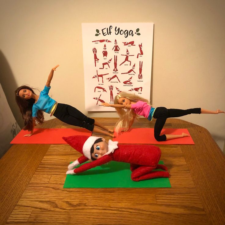 three dolls are posed on yoga mats in front of a poster