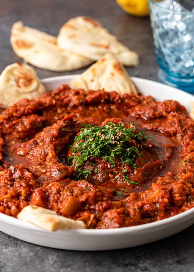 a white bowl filled with sauce and pita bread on top of a marble table