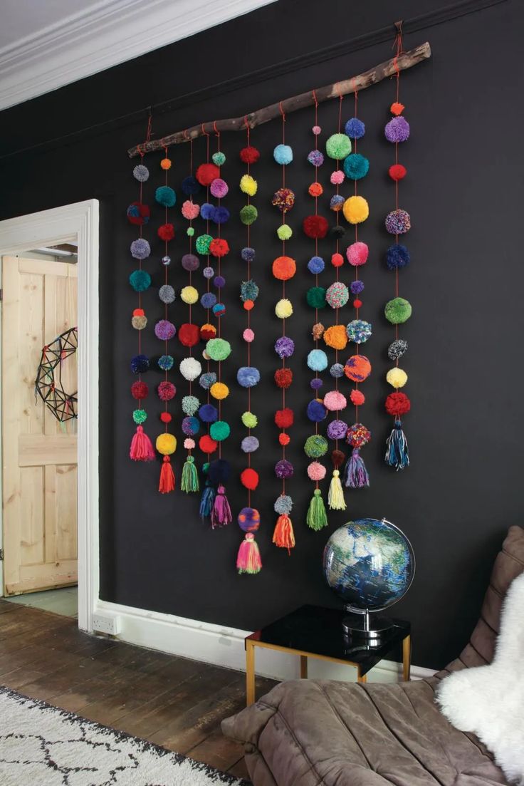 a living room with black walls and colorful pom - poms hanging on the wall