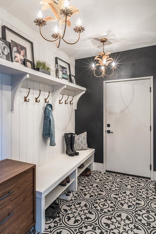 the entryway is decorated in black and white with an ornate tile floor, chandelier and coat rack