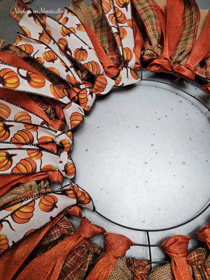 a wreath made out of fabric with pumpkins and leaves on the front, sitting on a table