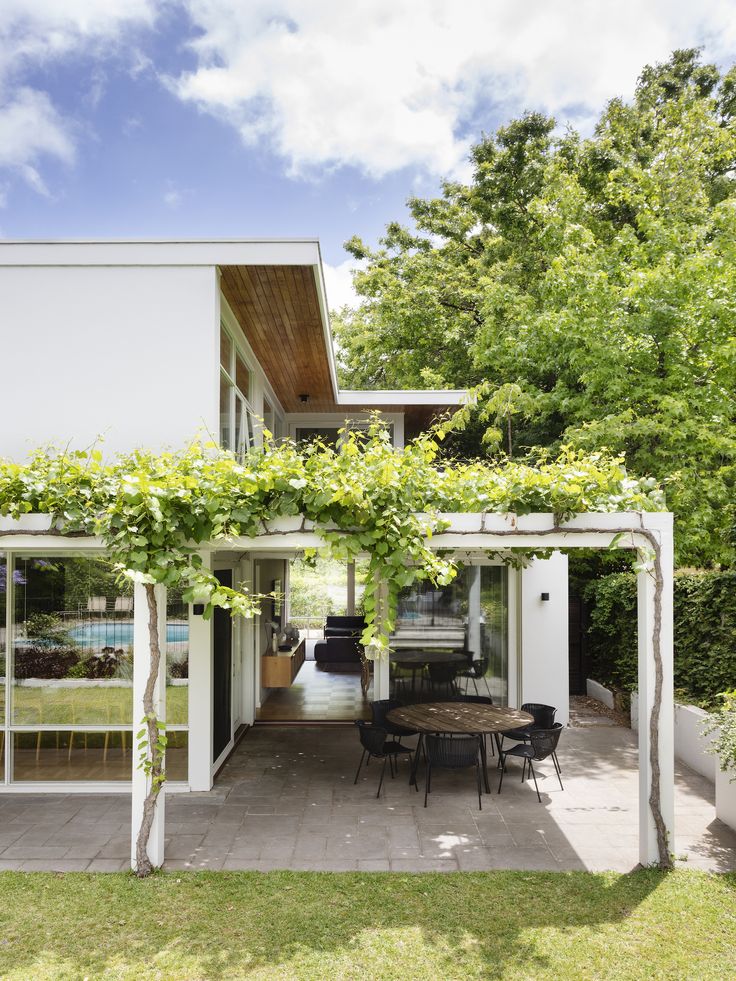 an outdoor dining area with table and chairs under a pergolated trellis on the roof