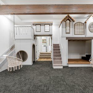 an indoor play area with stairs, slide and dog house in the middle of it