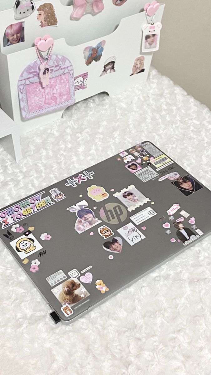 an open laptop computer sitting on top of a white bed covered in lots of stickers