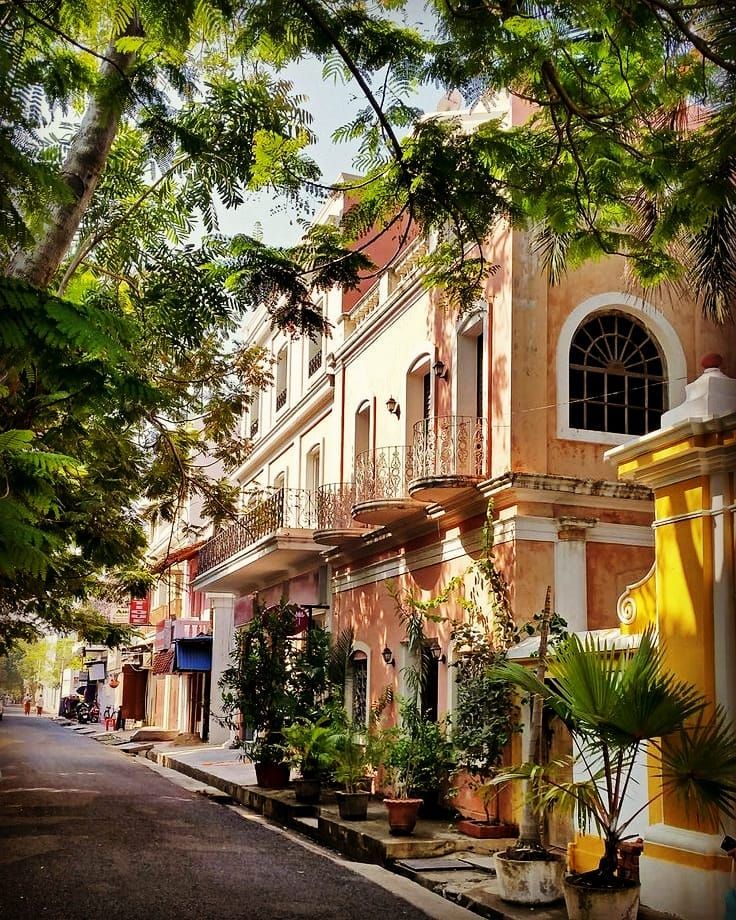 an old building with potted plants on the side of the street in front of it