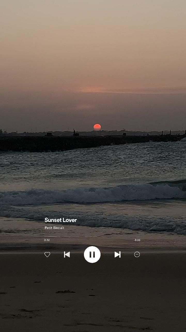 the sun is setting over the ocean with music player on it's left side