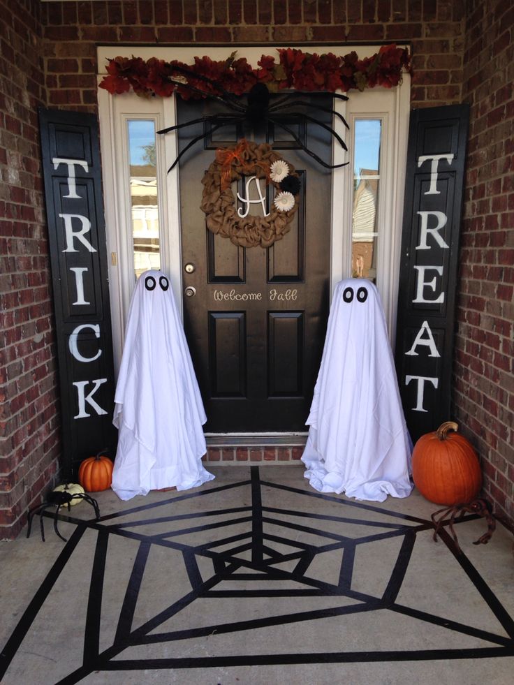 two halloween decorations on the front door of a house with ghost faces and pumpkins