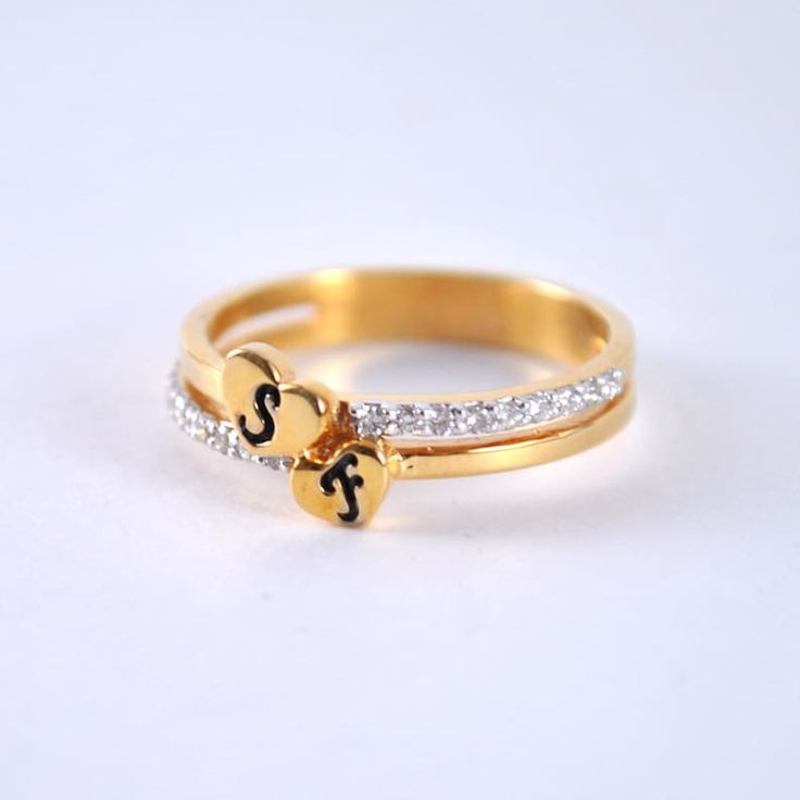 two gold rings with initials and diamonds on each ring, one has a small heart in the middle