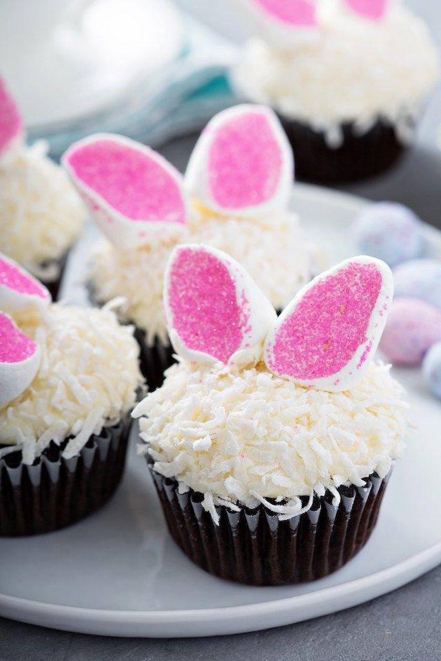 cupcakes decorated with bunny ears and white frosting on a plate stock photo