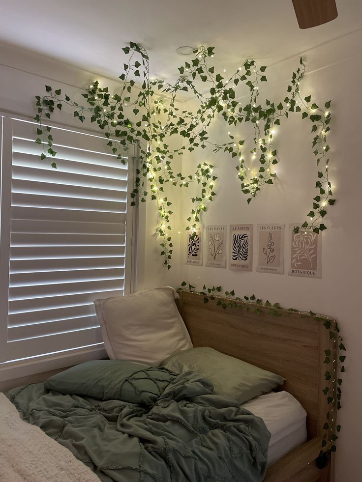 an unmade bed with ivy growing on the wall above it and lights hanging from the ceiling