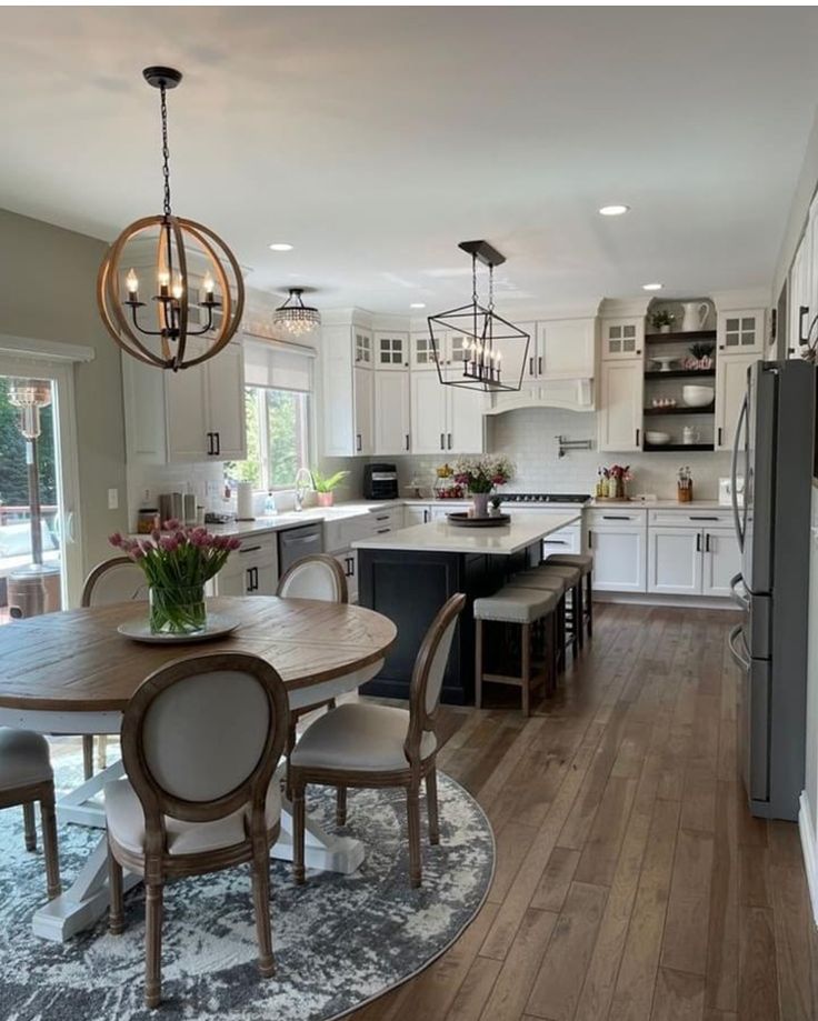 a kitchen and dining room with white cabinets, wood floors and an island in the middle