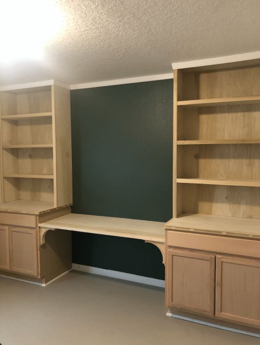 an empty room with two wooden shelves and cupboards in the middle, one is empty