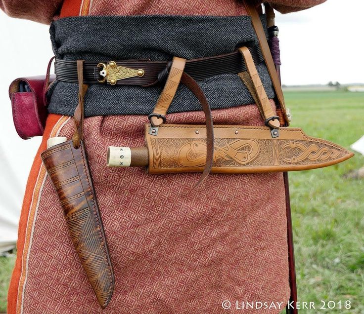 a man in an orange and brown outfit holding a knife with two knives attached to it