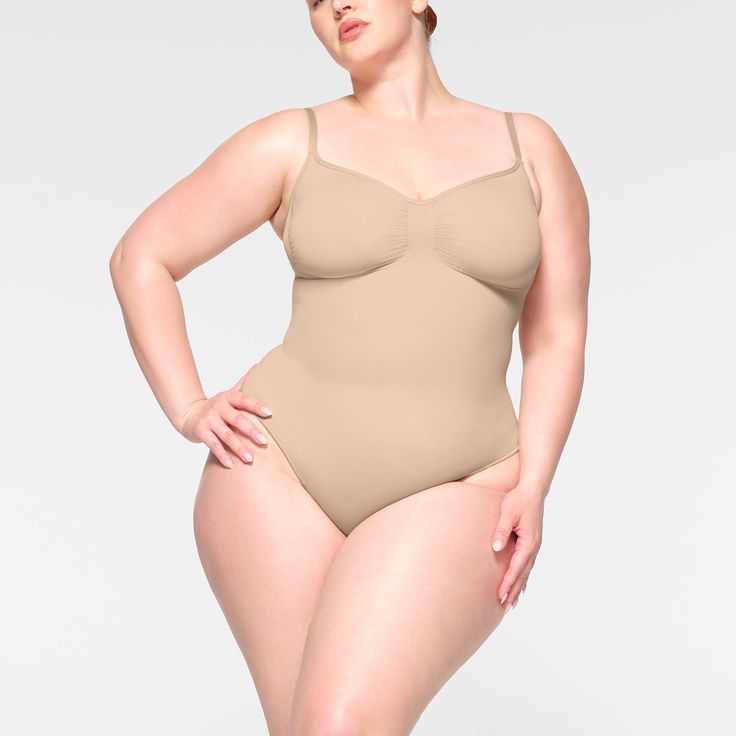 The internet’s favorite sculpting bodysuit, updated for an even better fit. This waist-cinching style enhances your shape with extra compression at the core and waist and has perfectly-placed style lines that flatter your bust. Features adjustable straps, a wide crotch for added coverage, and a cotton gusset with snap closure. Fits true to size. | SKIMS Thong Bodysuit | Light Neutral | Seamless Sculpt Sculpting Bodysuit, Cinched Waist, Polished Look, Luxury Fabrics, Kim Kardashian, Shapewear, Suits You, Body Shapes, Snap Closure