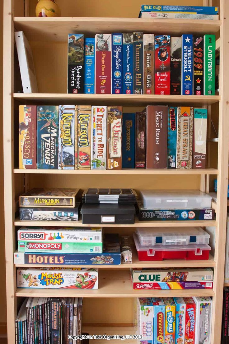 a book shelf filled with lots of books and video game controllers on top of it