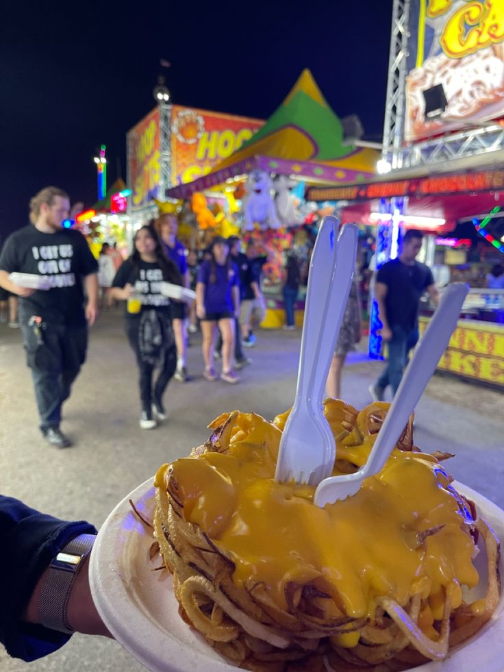 a white plate topped with lots of pancakes covered in cheese and sauce next to people