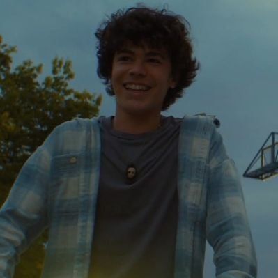 a young man is standing in front of a basketball hoop and smiling at the camera