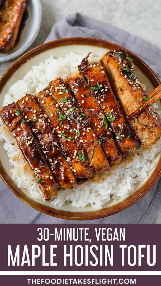 a plate with tofu on top of rice and chopsticks in the middle