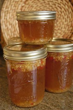 four jars filled with jam sitting on top of a counter next to a basket and wicker place mat