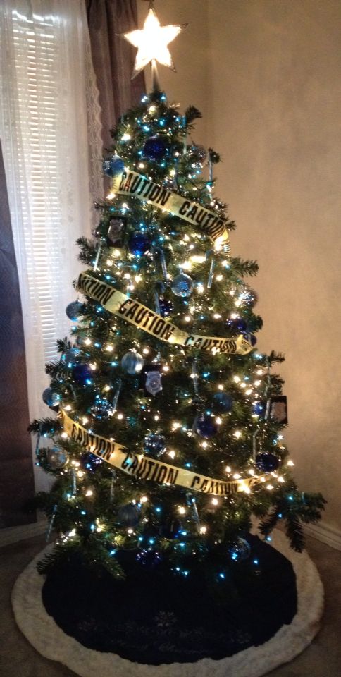 a decorated christmas tree with blue and gold ribbons on it's top, in front of a window