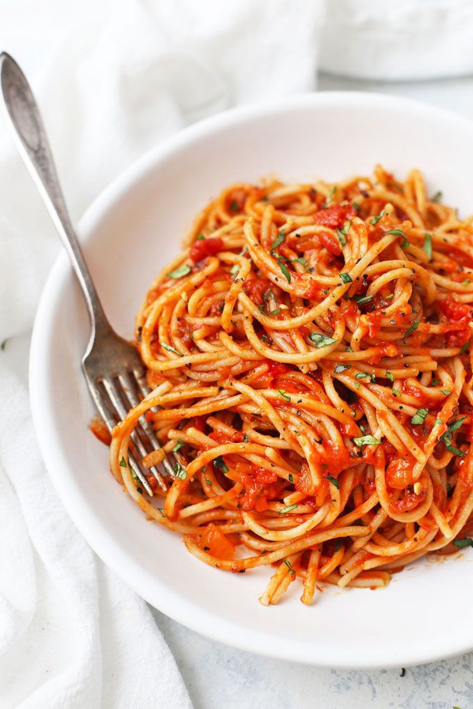 a white bowl filled with spaghetti and tomato sauce