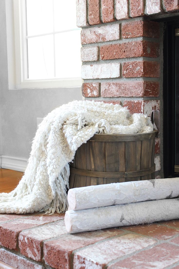 a blanket sitting on top of a wooden barrel next to a fire place in front of a brick wall