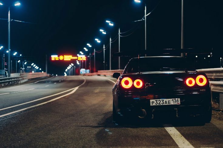 a car is parked on the side of the road at night with its lights on