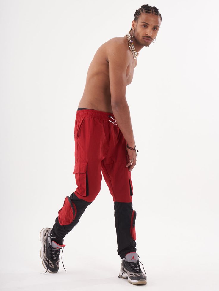 Double-color red and black joggers with four functional cargo pockets on the knees and elastic ankles. FEATURES Slim Fit Made up of 95% Cotton and 5% Elastane Jogger comfort Drawstring waist SIZE GUIDE Model's height and weight: 6"1 feet & 180 lbs. (185 cm & 82 kg ) Model wears size: L Red Sports Joggers With Elastic Waistband, Functional Cargo Jeans For Streetwear, Sporty Cargo Style Joggers For Streetwear, Red Athleisure Bottoms For Streetwear, Utility Streetwear Joggers With Functional Pockets, Red Athleisure Bottoms With Pockets, Utility Joggers With Functional Pockets For Streetwear, Red Cargo Pants For Streetwear, Functional Streetwear Joggers With Hip Pockets