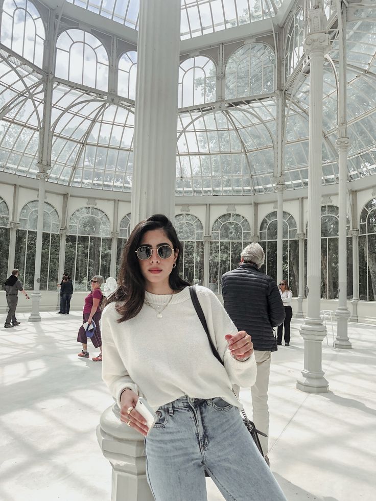 a woman posing for the camera in a large building with lots of glass and columns