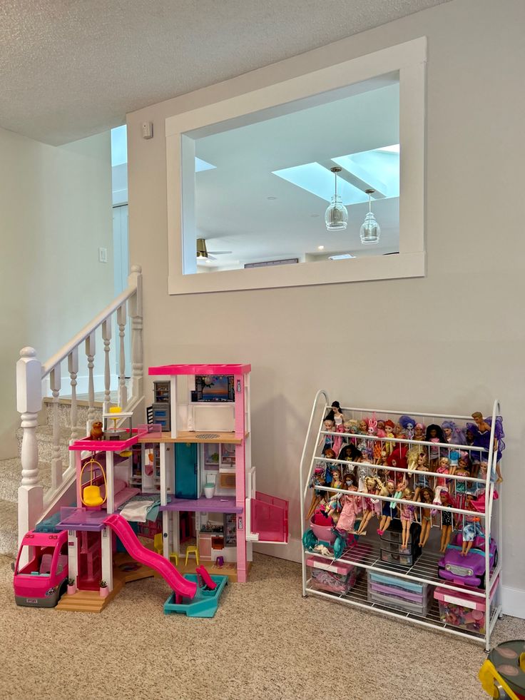 a room filled with lots of toys next to a stair case in front of a window