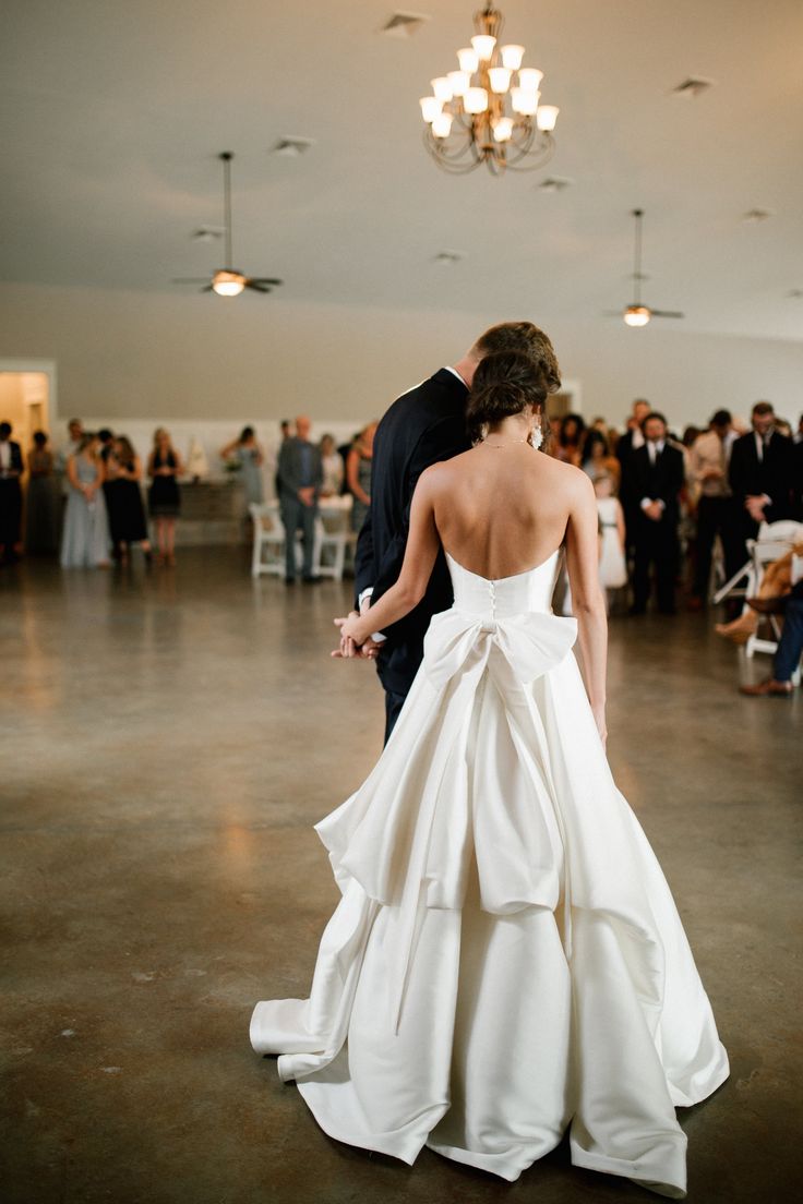 a bride and groom dance together in the middle of a large room full of people