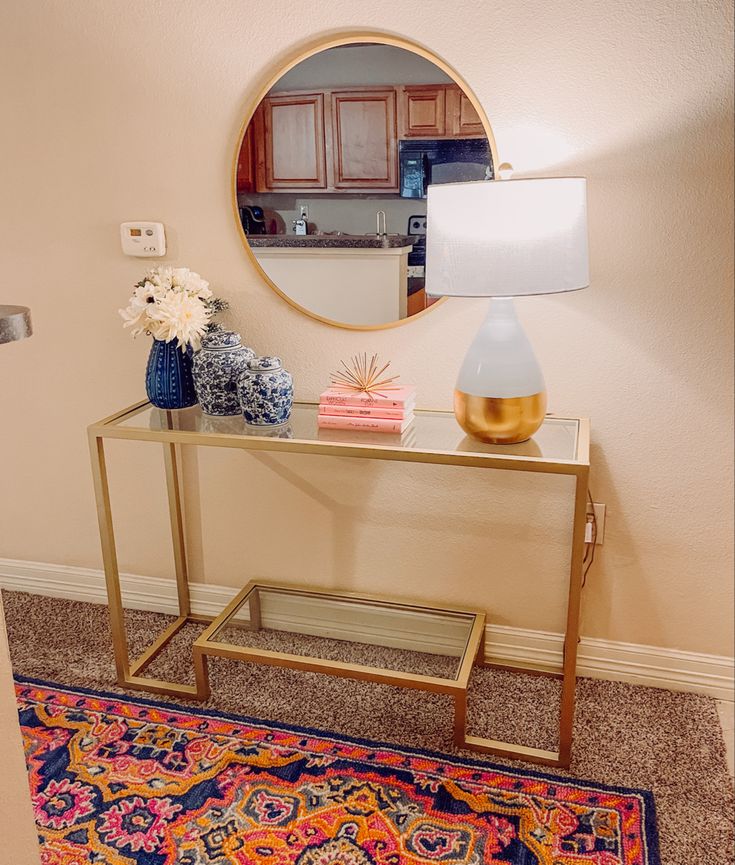 a table with a mirror, vase and lamp on it in front of a door