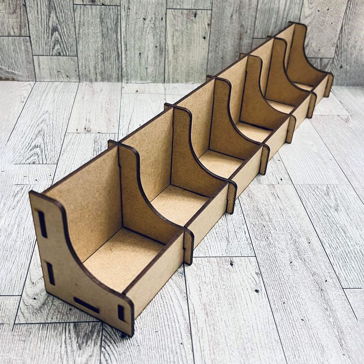 an empty cardboard box sitting on top of a white wooden floor next to a wall